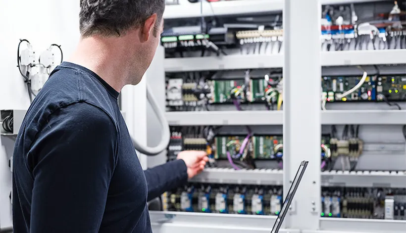 Electrician working on electronics cabinet