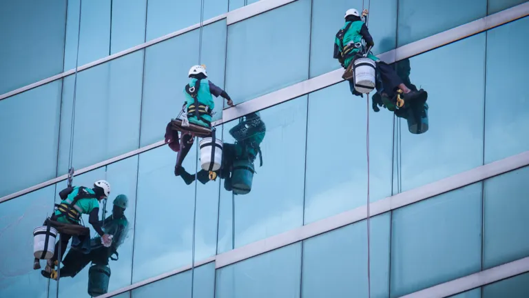 Group of workers cleaning windows service on high rise building